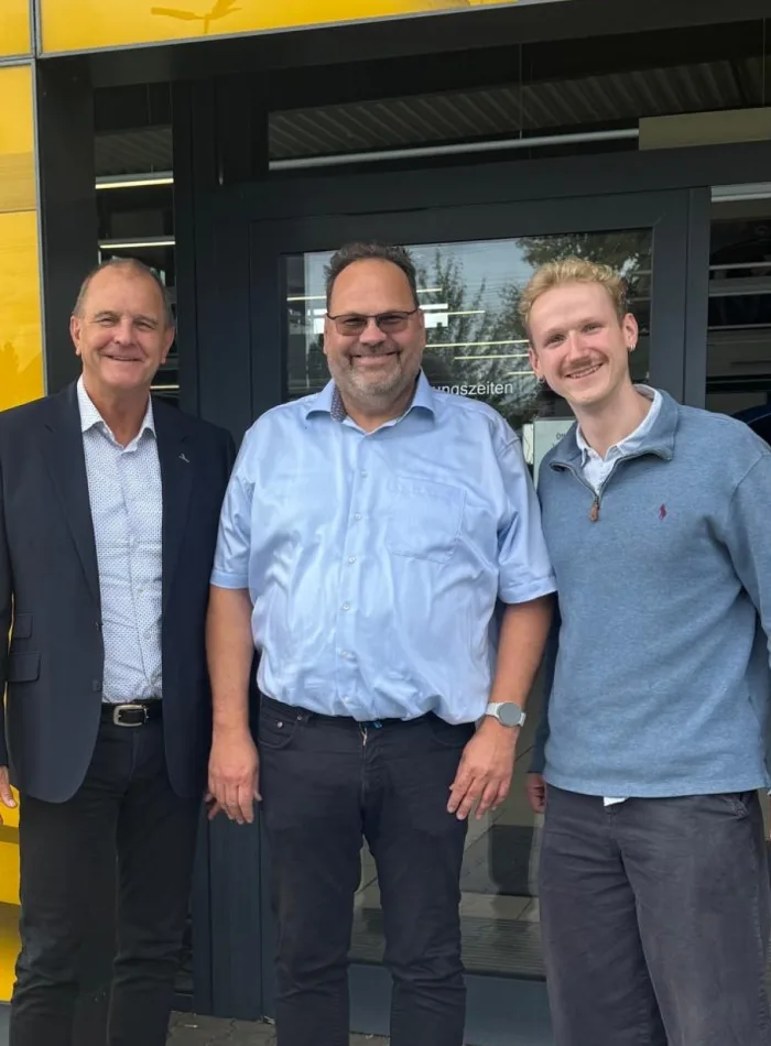 Drei Menschen vor dem Autohaus Günther & Schmitt